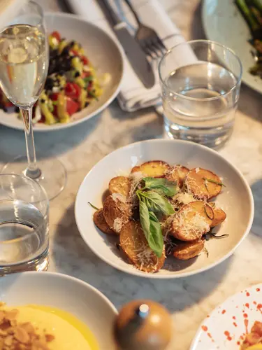 Dinner table with food and red wine being poured into glasses